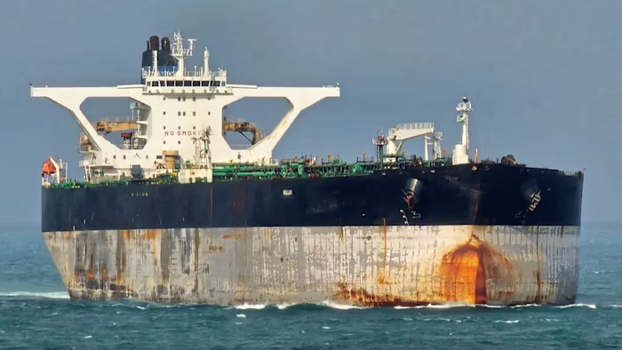 La petroliera Bella 1 in mare, con scafo e sovrastruttura striati di ruggine, fotografata dalla parte anteriore a livello dell'acqua.