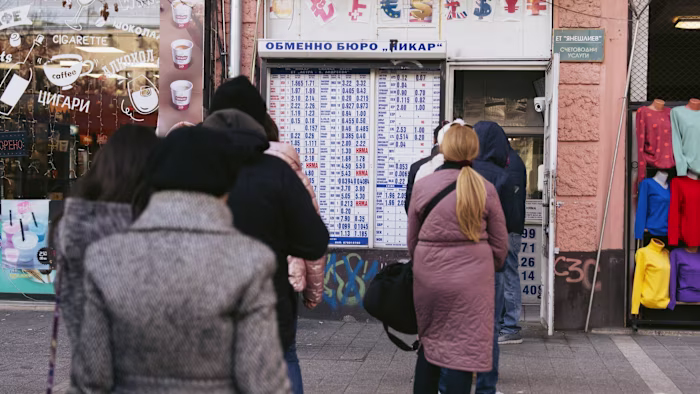 People stand in line at a currency exchange displaying rates in Sofia, Bulgaria, ahead of the euro’s adoption.