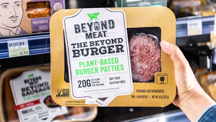 A shopper holds a Beyond Meat plant-based burger patties in a supermarket aisle