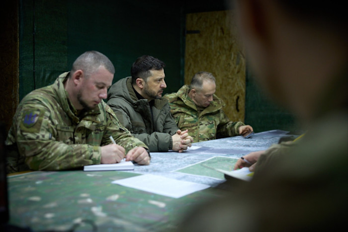 Volodymyr Zelenskyy siede al centro a un tavolo con personale militare